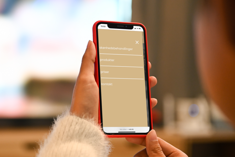 Kvinde som holder Iphone der viser hjemmeside lavet af Human Hero Webdesign. Web developer i København. Squarespace, WordPress og Shopify.